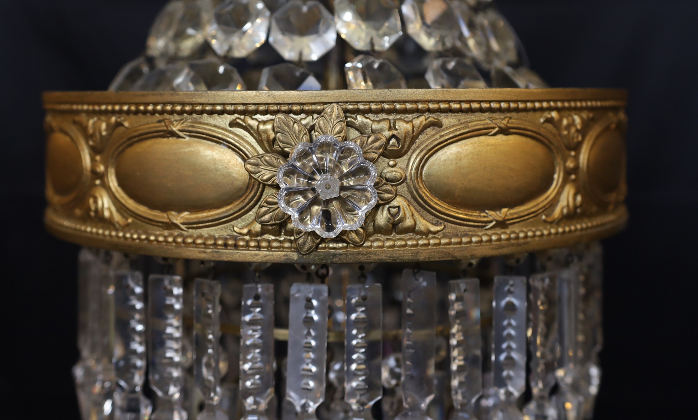 An early 20th century English ormolu and cut glass bag chandelier, hung with octagonal cut drops and spear shaped lustres with four tiers to the base, height 75cm. diameter 35cm